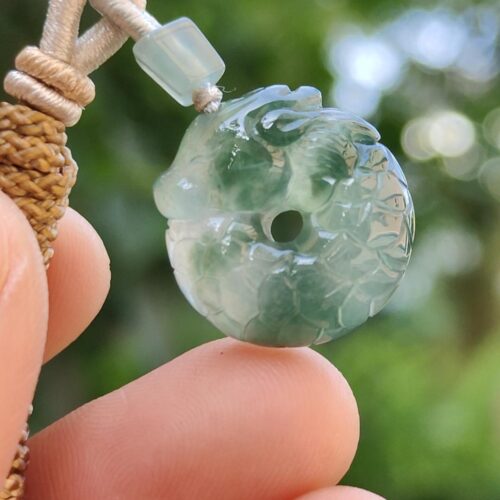 a hand holding a jade pendant