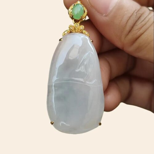 a hand holding a jade pendant