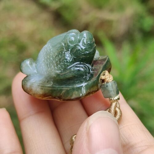 a hand holding a jade frog
