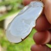 a hand holding a white jade pendant