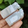 a hand holding a pair of carved jade seals