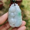 a hand holding a jade pendant