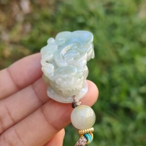 a hand holding a jade pendant
