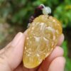 a hand holding a carved stone pendant