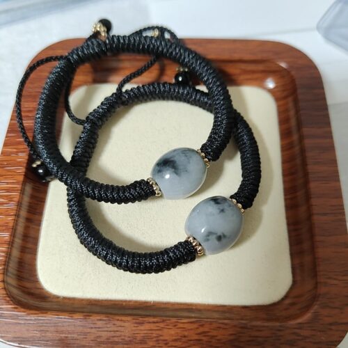 a black and white bracelet on a wooden tray