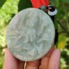 Una mano sosteniendo un medallón de jade.