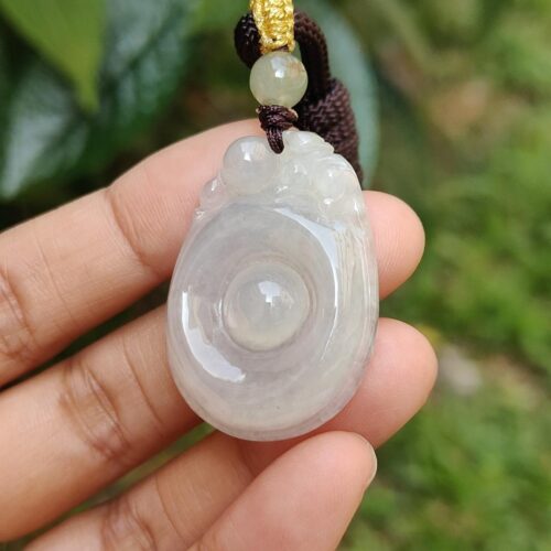 Una mano sosteniendo un colgante de jade.