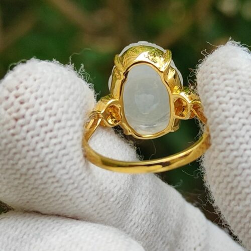 a hand wearing a glove holding a gold ring