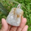 Una mano sosteniendo un colgante de piedra.