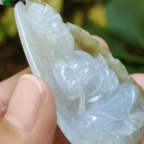 a hand holding a jade pendant