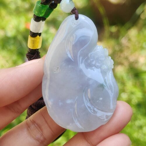 a hand holding a jade pendant