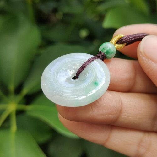 une main tenant un pendentif en jade