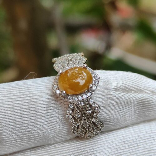 a ring with a yellow stone on a white cloth