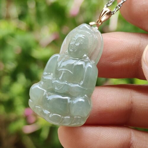 a hand holding a jade pendant