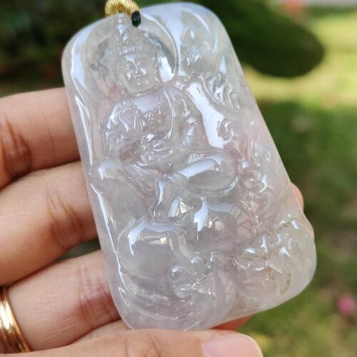 a hand holding a jade pendant