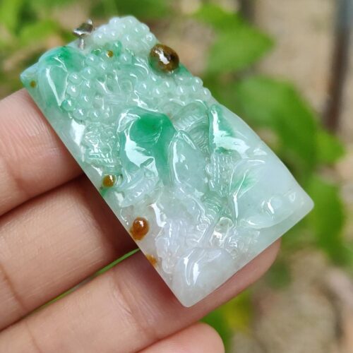 a hand holding a jade pendant