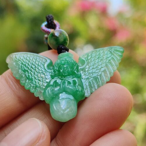 a hand holding a green stone angel