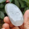 a hand holding a jade pendant