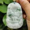 a hand holding a jade pendant