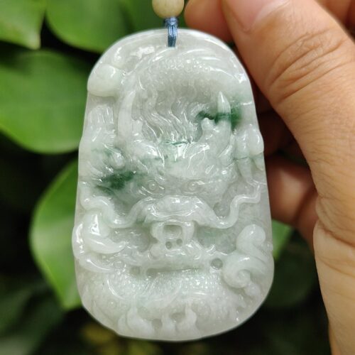 a hand holding a jade pendant