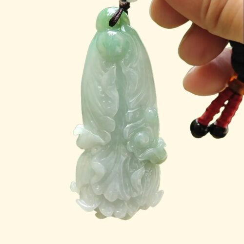 a hand holding a jade pendant