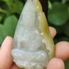 a hand holding a jade pendant