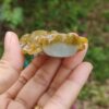 a hand holding a small yellow and white stone