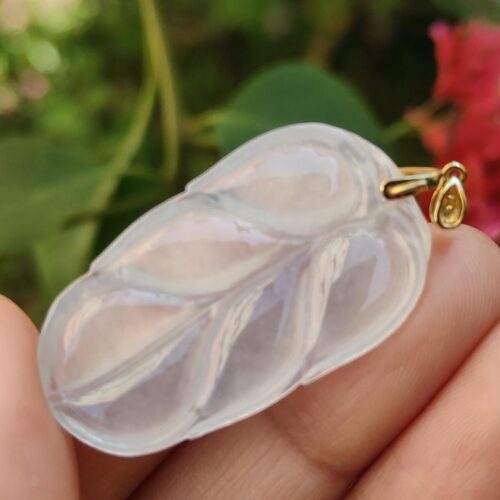 a hand holding a clear leaf pendant