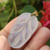 a hand holding a clear plastic leaf pendant
