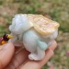 a hand holding a small white and yellow stone statue