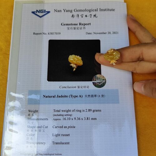 a hand holding a piece of paper with a piece of yellow stone