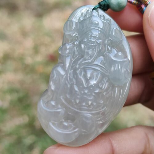 a hand holding a jade pendant