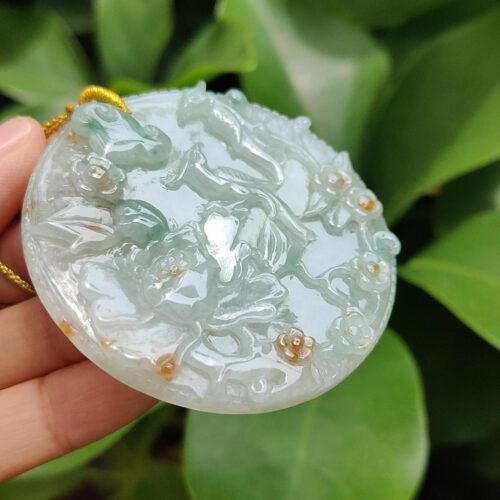 a hand holding a jade pendant