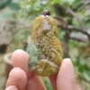 a hand holding a green and yellow pendant