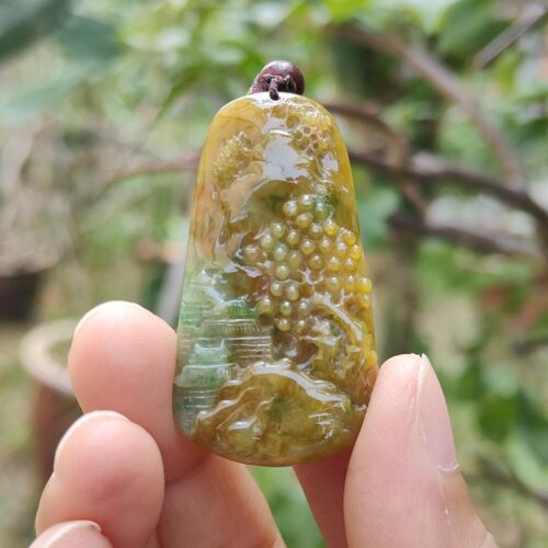a hand holding a green and yellow pendant