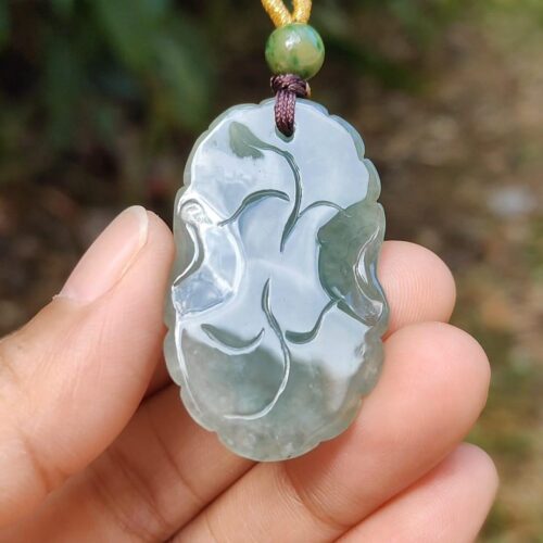 a hand holding a jade pendant