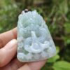 une main tenant un objet en jade