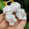 a hand holding a pair of white jade elephants