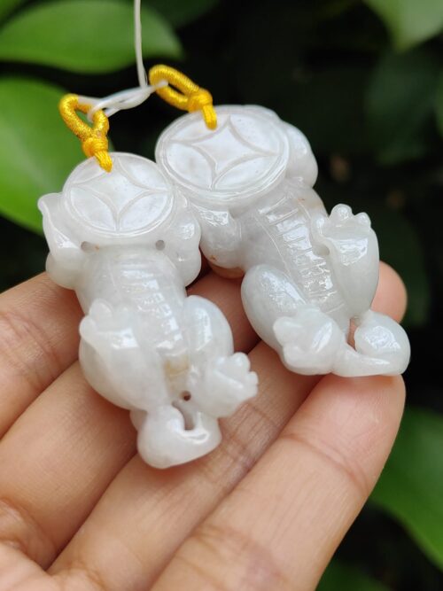a hand holding a pair of white jade elephants