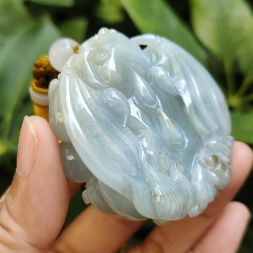 une main tenant un objet en jade