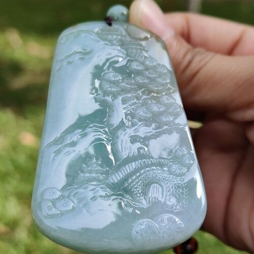 a hand holding a jade pendant
