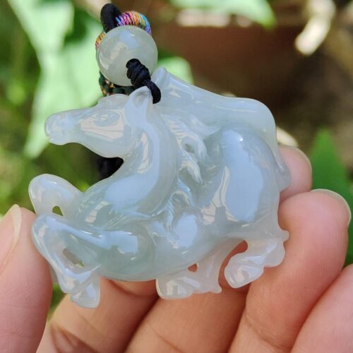 a hand holding a jade horse pendant