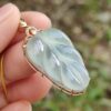 une main tenant un pendentif en jade