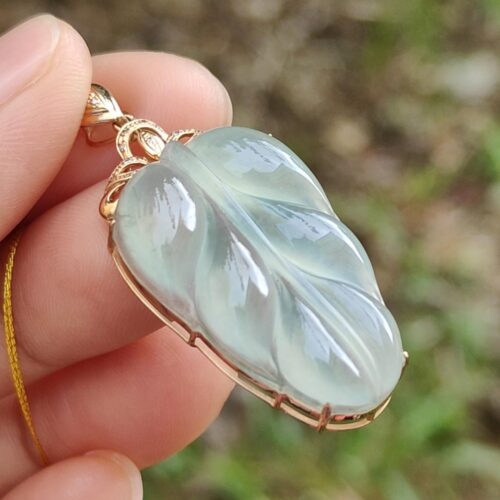 une main tenant un pendentif en jade