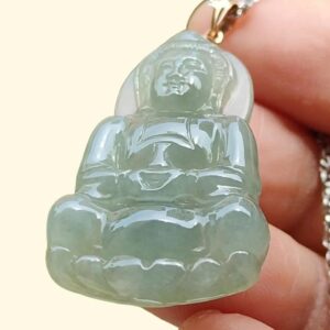 a hand holding a jade pendant