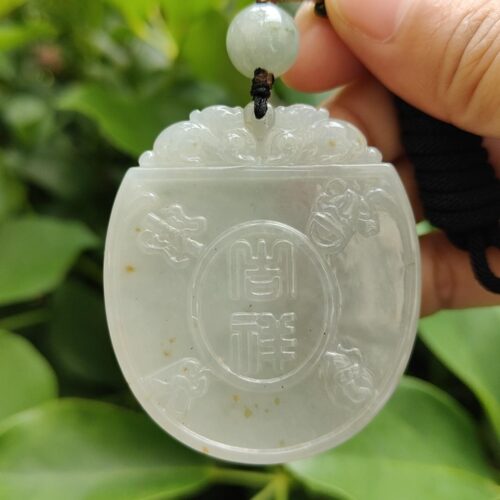 une main tenant un pendentif en jade