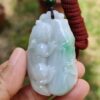 a hand holding a jade pendant