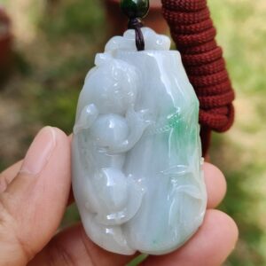 a hand holding a jade pendant