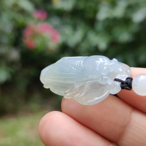 a hand holding a jade bug pendant