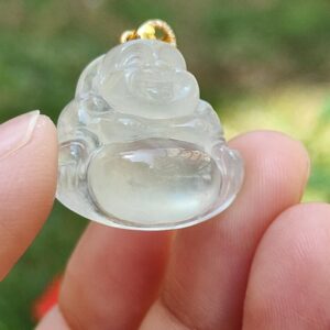 a hand holding a small white buddha pendant